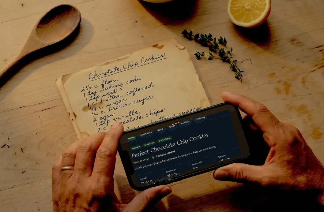Hands holding a phone over a handwritten Chocolate Chip Cookies card, with the recipe open in Capseta